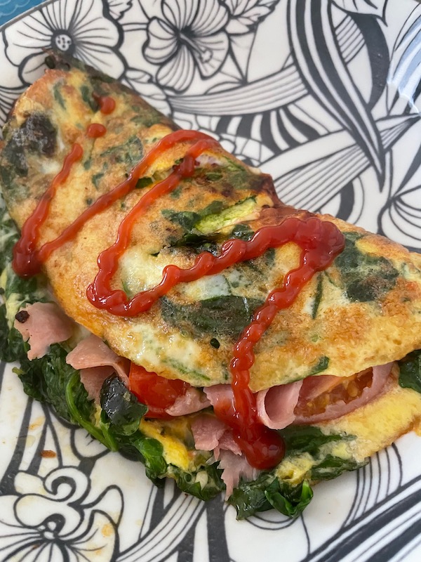 Ham, cheese, tomato, and spinach omelet with ketchup