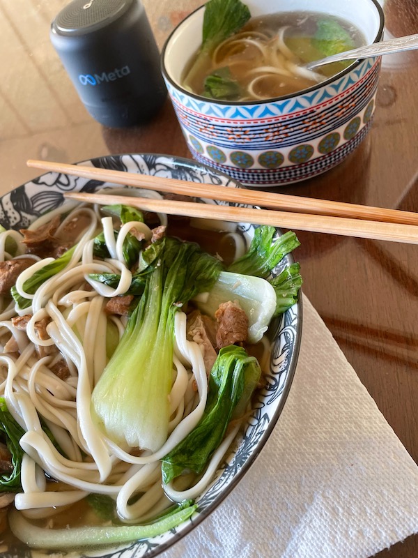 Bowl of noodles in soup, bokchoy, and meat