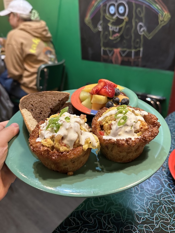 Two hashbrown quiches with egg inside and fruit on the side