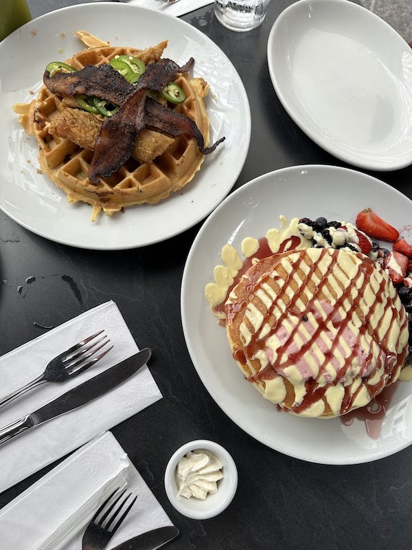 Plate of chicken and waffles and plate of berry pancakes