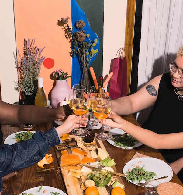 Group clinking glasses with charcuterie plate on table